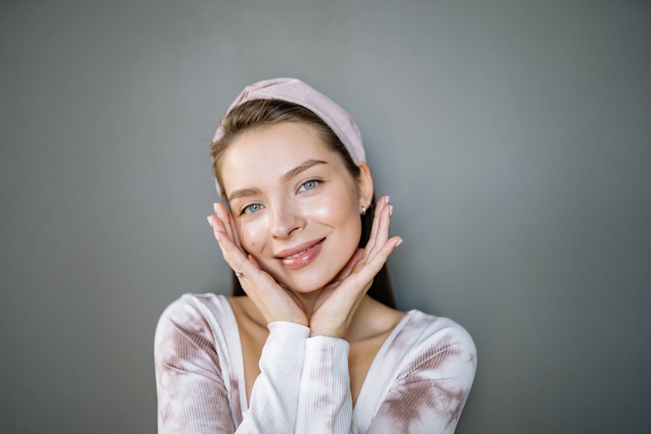 our-story Portrait of a smiling woman with a headband against a gray background.